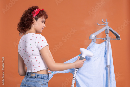 Steamer for ironing shirts and other clothing. Girl with curly hair. photo