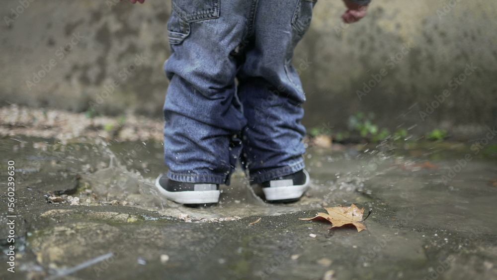 Child jumping into water puddle. Toddler wearing boots splash into puddle4 Child jumping into water puddle. Toddler wearing boots splash into puddle4