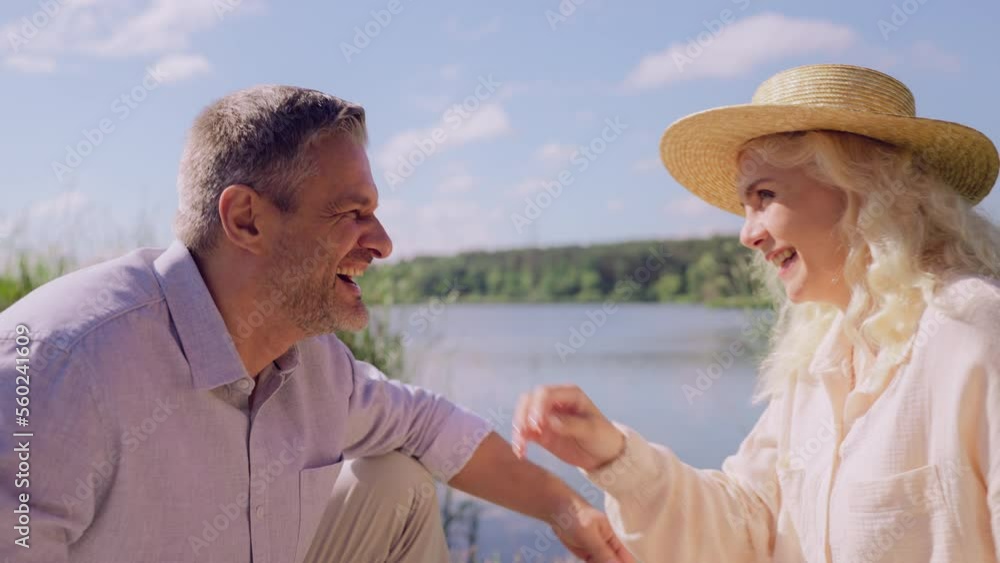 Happy Caucasian couple having fun by the lake, telling stories, romantic date Happy Caucasian couple having fun by the lake, telling stories, romantic date