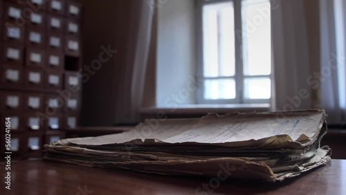 The wind shakes the pages of a vintage archival document. A close-up of a folder with old documents lies on a table in an archive or file cabinet building.