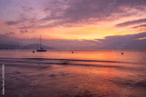 Beautiful sunset over the sea with red and purple colored clouds and water with silky effect from long exposure © Alessio