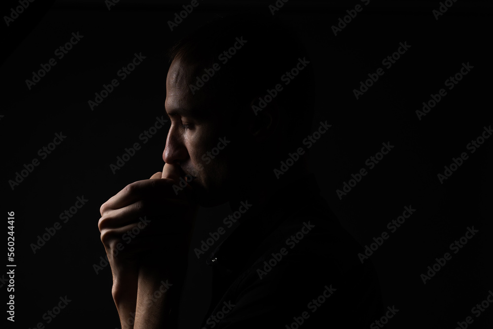 Man with clasped hands praying on black background Man with clasped hands praying on black background