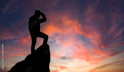 The hiker on top of the mountain. A young, athletic man stands on a high rock. Sporty man standing on stone against valley at sunset, active life concept