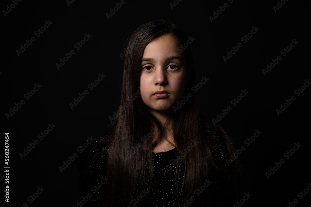 Portrait of sad little girl on black background