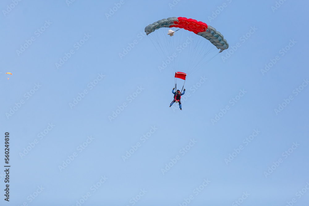 Skydiver with a little canopy of a parachute on the background a blue sky, close-up. Skydiver under parachute Skydiver with a little canopy of a parachute on the background a blue sky, close-up. Skydiver under parachute