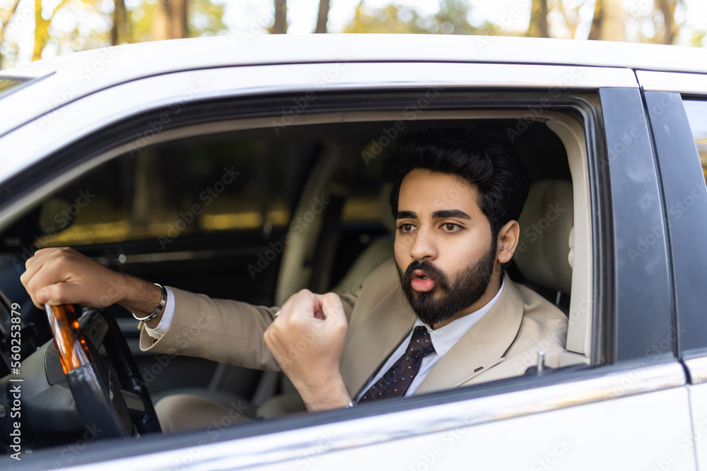 Excited man driving a car showing fist from car Excited man driving a car showing fist from car