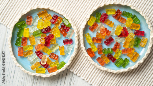 Two plates of vibrant and colorful jelly gummies on a white table. perfect for any confectionery related project or as a treat for kids