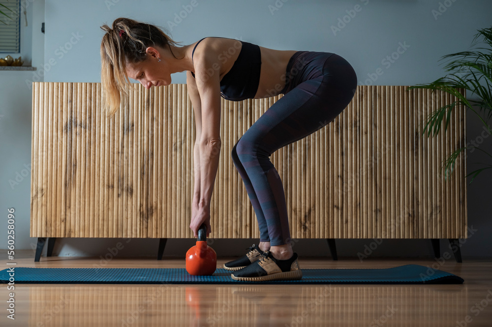 Side view of a woman working out at home making a deadlift exercise - obrazy, fototapety, plakaty 