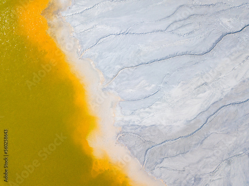 Aerial view of an abandoned Romanian village drowned beneath toxic lake of fluorescent yellow sludge in Geamana,Rosia Montana,Transylvania. Yellow, orange, white abstract background. photo
