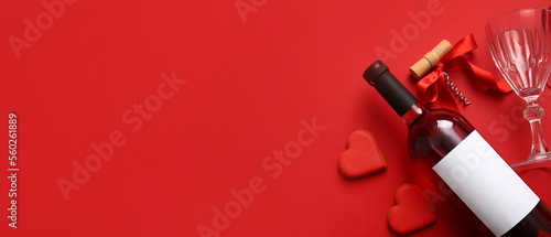 Bottle of wine, glass, corkscrew and heart shaped cookies on red background with space for text. Valentines Day celebration