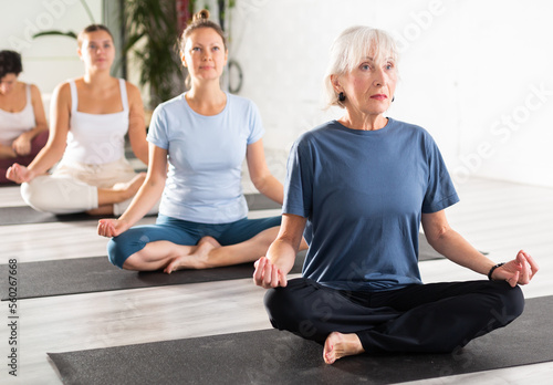 Group of woman making yoga meditation in lotus pose at gym