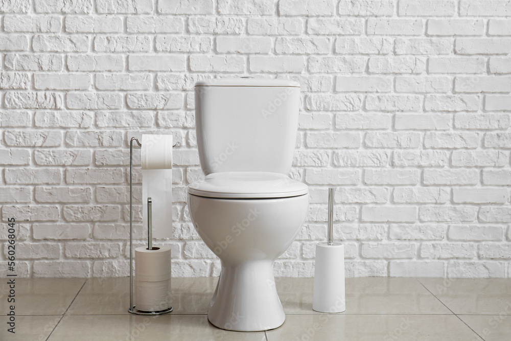 Modern toilet bowl near white brick wall Modern toilet bowl near white brick wall