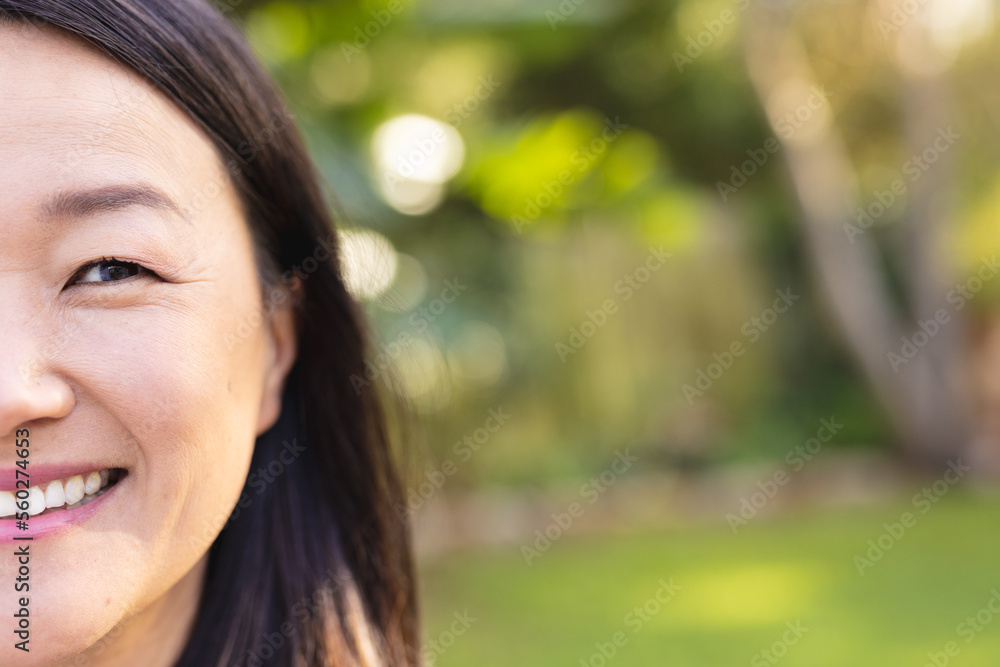 Portrait of happy asian woman looking at camera and smiling in garden with copy space Portrait of happy asian woman looking at camera and smiling in garden with copy space