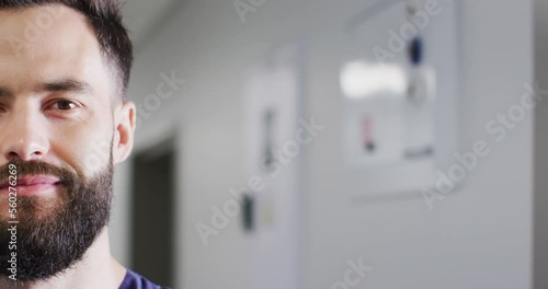 Video half face portrait of smiling, bearded caucasian male medical worker in corridor, copy space photo
