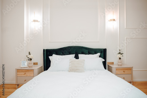 Luxury and stylish bedroom interior with king size bed, white bedding and modern light fixtures and beautiful nightstands