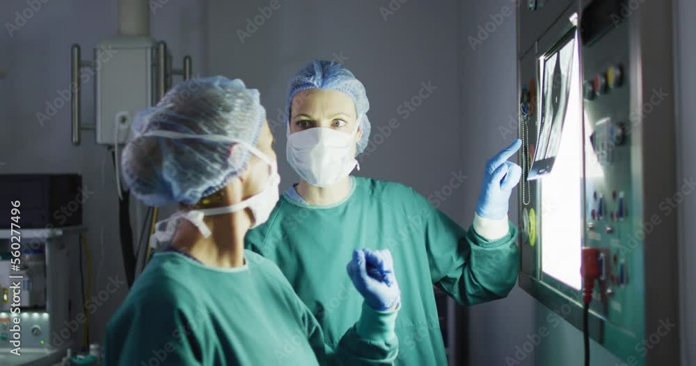 Video of two diverse female surgeons discussing x-ray on lightbox in operating theatre Video of two diverse female surgeons discussing x-ray on lightbox in operating theatre
