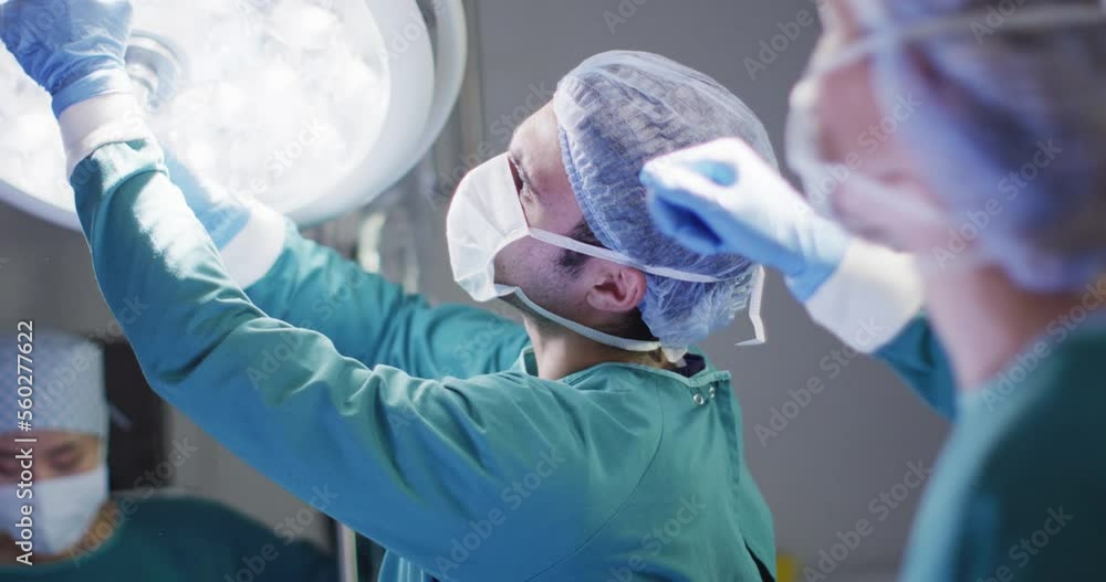 Video of caucasian female surgeon and male surgical assistant preparing theatre light for operation Video of caucasian female surgeon and male surgical assistant preparing theatre light for operation