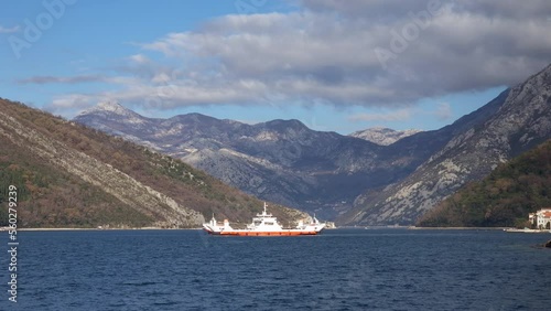 Ferry boat on the water - beautiful Mediterranean coast seascape with sea and mountains under clouds in the sky. Transport of motor vehicles across the Verige strait in Bay of Kotor, Montenegro. photo