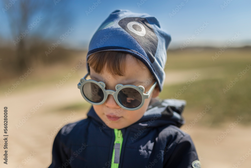 Portrait of a small boy in bear shaped sunglasses and blue hat o Portrait of a small boy in bear shaped sunglasses and blue hat o