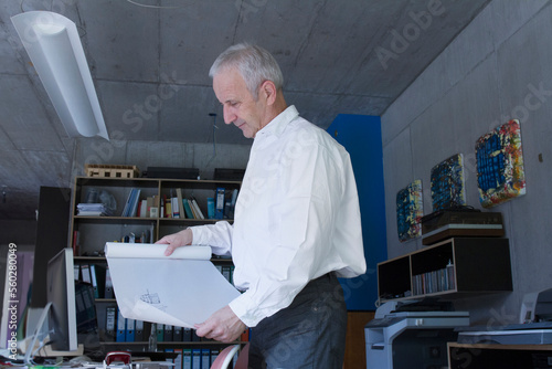 Senior businessman looking at blueprint in the office, Freiburg im Breisgau, Baden-Württemberg, Germany photo