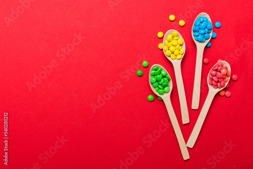 delicious colorful sweet candies on spoon on colored background . Confectionery decor top view with copy space