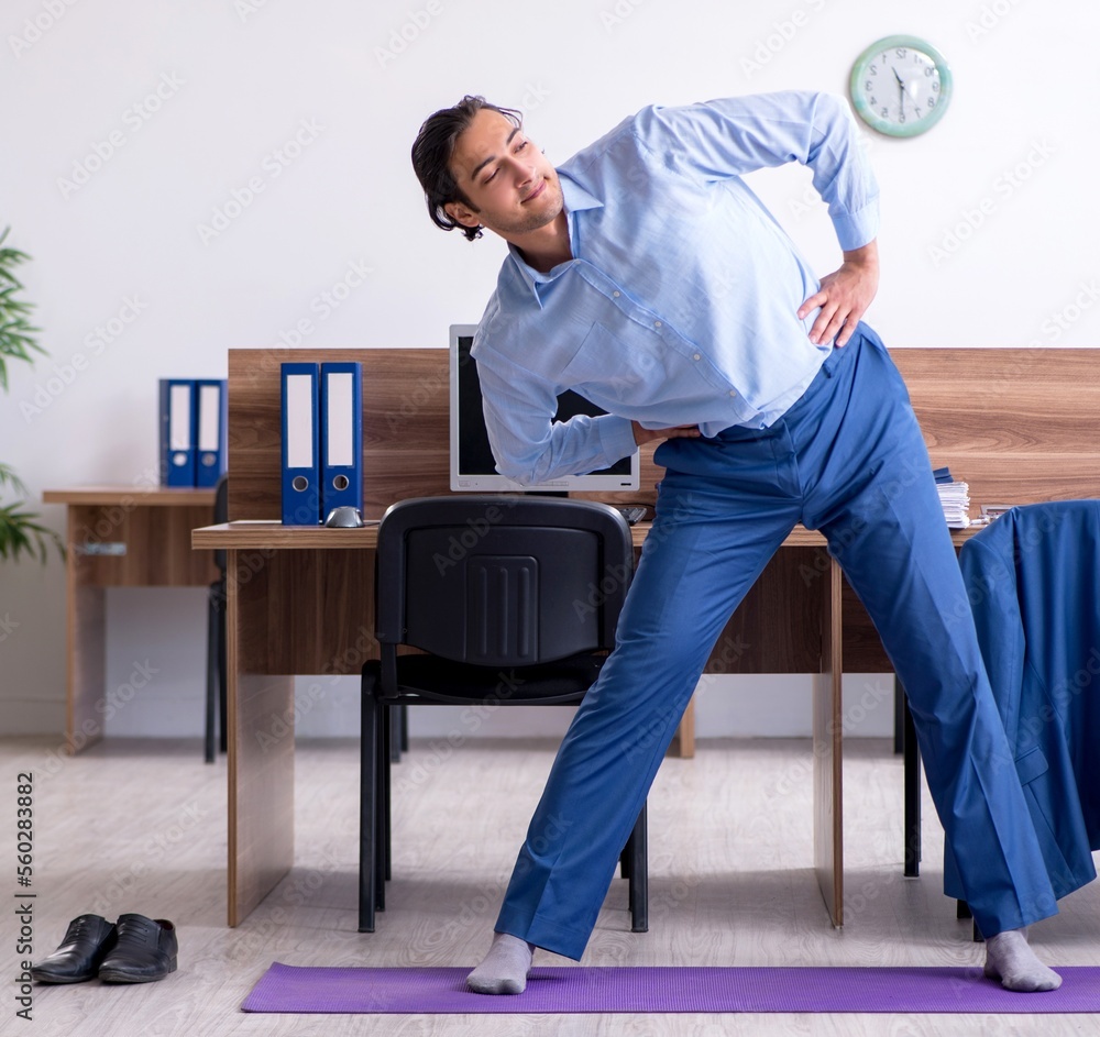 Young handsome businessman doing exercises at workplace Young handsome businessman doing exercises at workplace