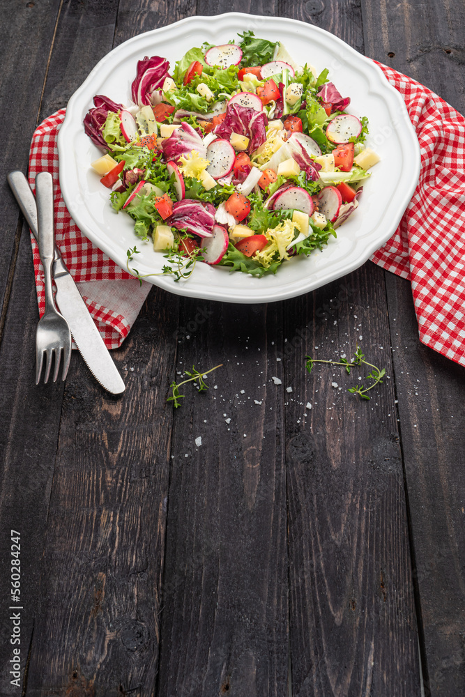Fresh salad with mixed greens radish cheese and tomato in a plate on wooden background. Italian Mediterranean or Greek cuisine. Vegetarian vegan food. Fresh salad with mixed greens radish cheese and tomato in a plate on wooden background. Italian Mediterranean or Greek cuisine. Vegetarian vegan food.