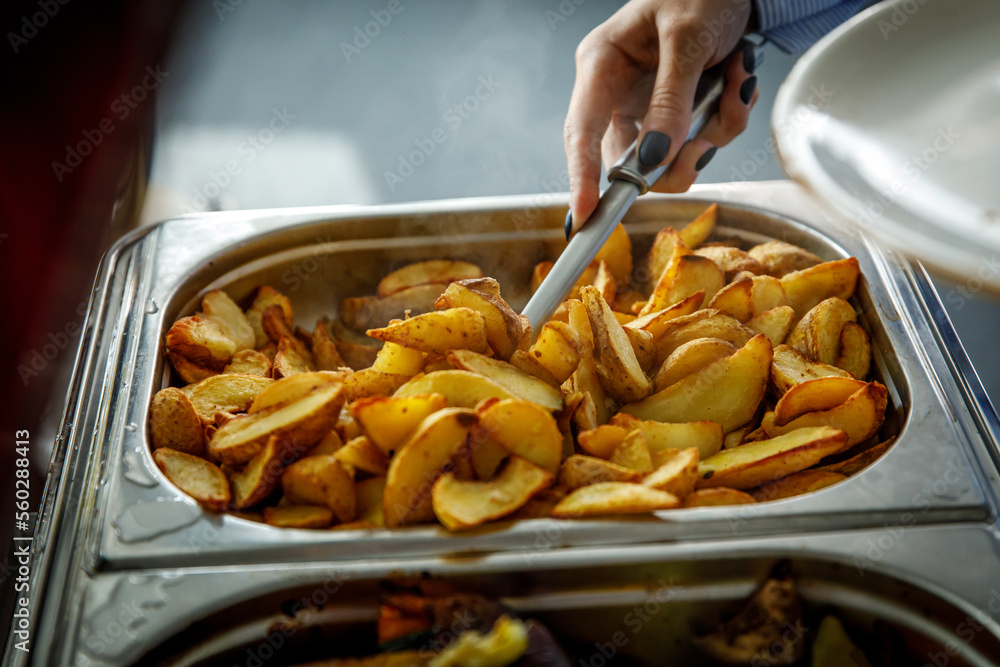 The guest puts potatoes on his plate. Buffet in the hotel.