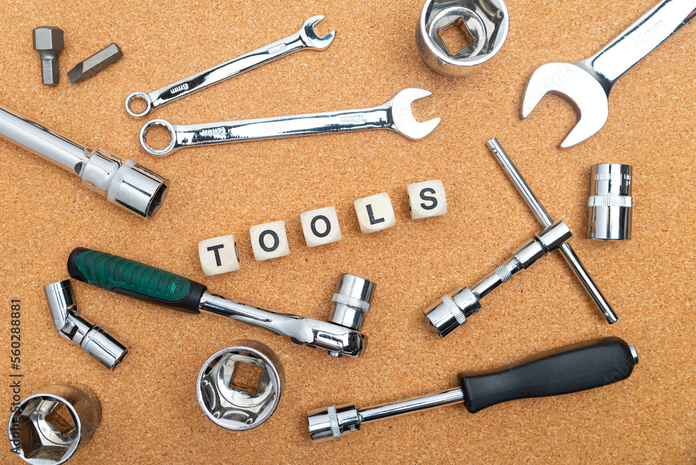 wrenches near the cubes with the inscription TOOLS on the cork table. View from above. wrenches near the cubes with the inscription TOOLS on the cork table. View from above.