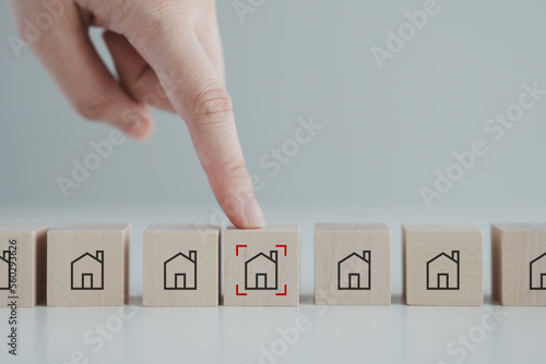Fototapeta Naklejka Na Ścianę i Meble -  Hand point to house icon with focus frame on wood block. Real estate, Property investment and asset management concept. Decision to choose best property with your right. Choosing suitable housing.