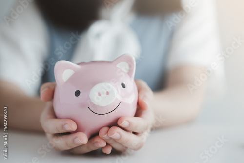 Female hand holding pink piggy bank. Save money for future or retirement and financial investment.