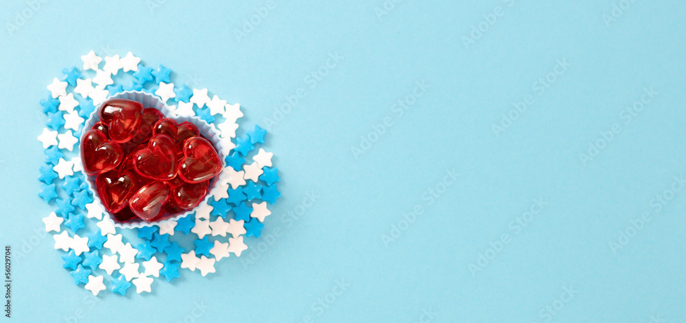 Muffin molds with red hearts and candy sprinkles on blue. Muffin molds with red hearts and candy sprinkles on blue.