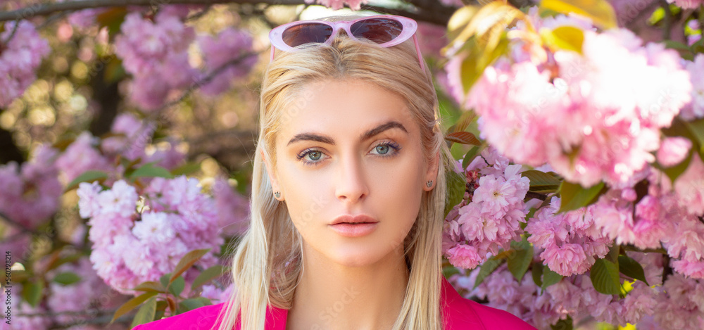 Obraz premium Sensual woman near sakura tree background, banner for website header. Portrait of sexy young woman. Smiling face of spring girls. Blossom female model.