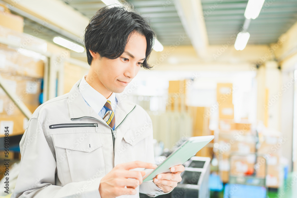 作業服を着て倉庫で在庫管理をする若いビジネスマン 作業服を着て倉庫で在庫管理をする若いビジネスマン