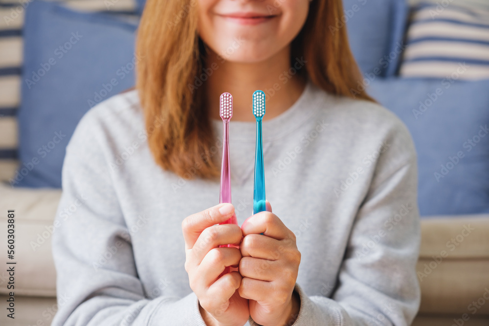 Closeup image of a young woman holding and showing two toothbrush Closeup image of a young woman holding and showing two toothbrush