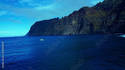 Small boat cruising Open Blue ocean In Front of high Rise Rocky Mounntains, Spain photo