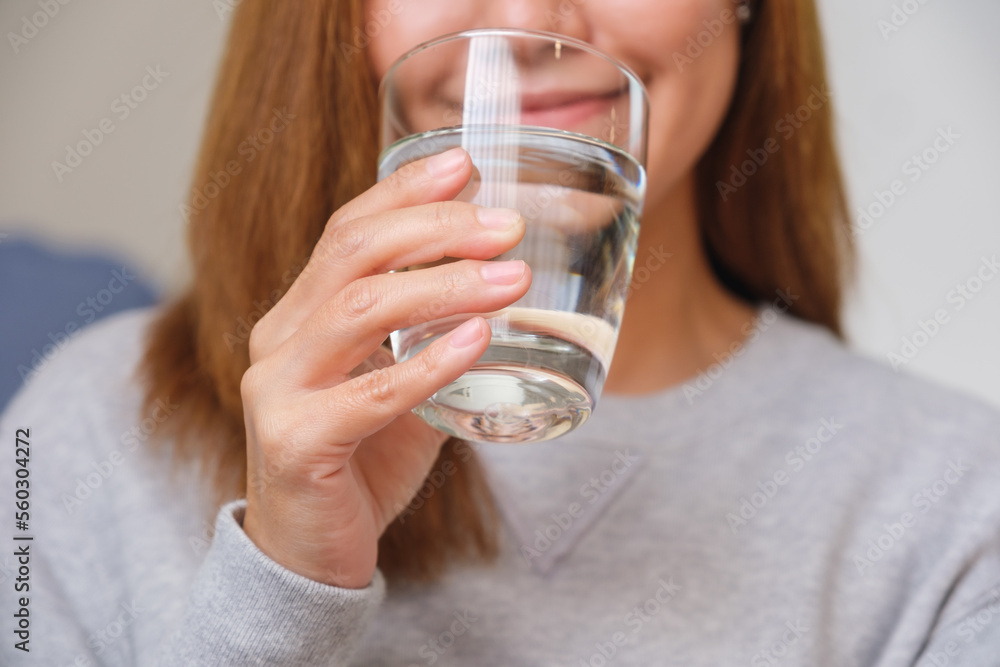 Closeup image of a young woman holding a glass of water to drink Closeup image of a young woman holding a glass of water to drink