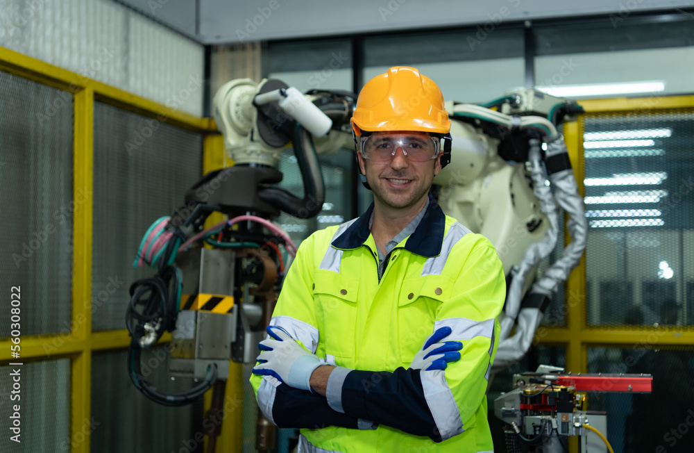 Portrait of engineering with a huge welding robot behind, it that has been inspected after use. Portrait of engineering with a huge welding robot behind, it that has been inspected after use.