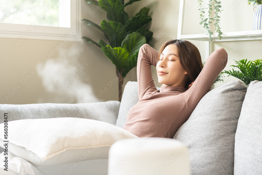 Modern air humidifier during relax or rest, happy asian young woman, girl enjoying aromatherapy steam scent from essential oil diffuser comfortable in living conditions room, apartment at home. Modern air humidifier during relax or rest, happy asian young woman, girl enjoying aromatherapy steam scent from essential oil diffuser comfortable in living conditions room, apartment at home.