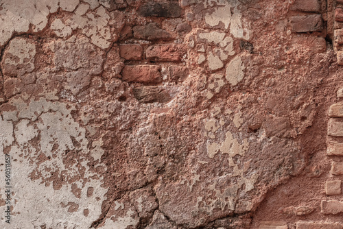 Abandoned old brick wall with damaged plaster and cracks