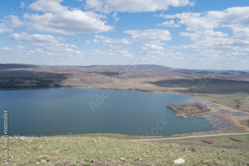 Beautiful sunny day at the top of the mountain. A wonderful view from the mountain to the lake with a spring landscape under the sunlight and a perfect sky. Blue sky with white clouds and blue lake