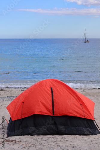 An orange camping tent on the beach with the pacific ocean in the background © Fabbox