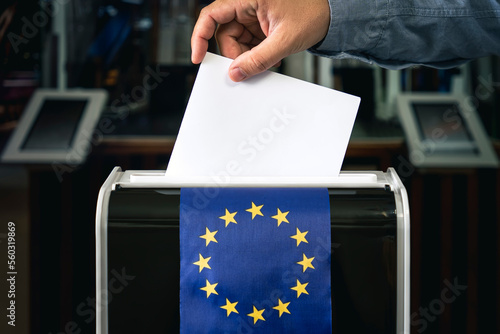 man putting ballot in box during elections in europe. copy space, flag of europe photo