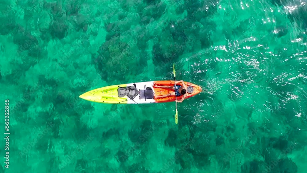 Aerial drone video of man enjoying sport kayak in tropical exotic landscape with crystal clear emerald sea Aerial drone video of man enjoying sport kayak in tropical exotic landscape with crystal clear emerald sea