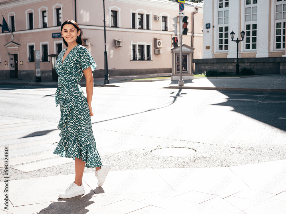 Young beautiful smiling hipster woman in trendy summer dress clothes. Sexy carefree model posing on the street background at sunset. Positive brunette female. Cheerful and happy. Full length Young beautiful smiling hipster woman in trendy summer dress clothes. Sexy carefree model posing on the street background at sunset. Positive brunette female. Cheerful and happy. Full length