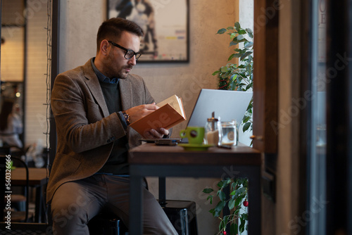 Businessman Reading Book while Sitting in Cafe