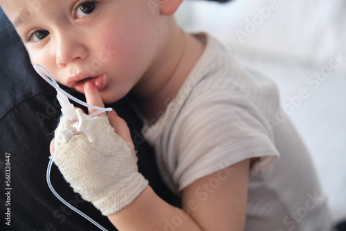 little boy in the hospital with intravenous line in his hand hugging his father