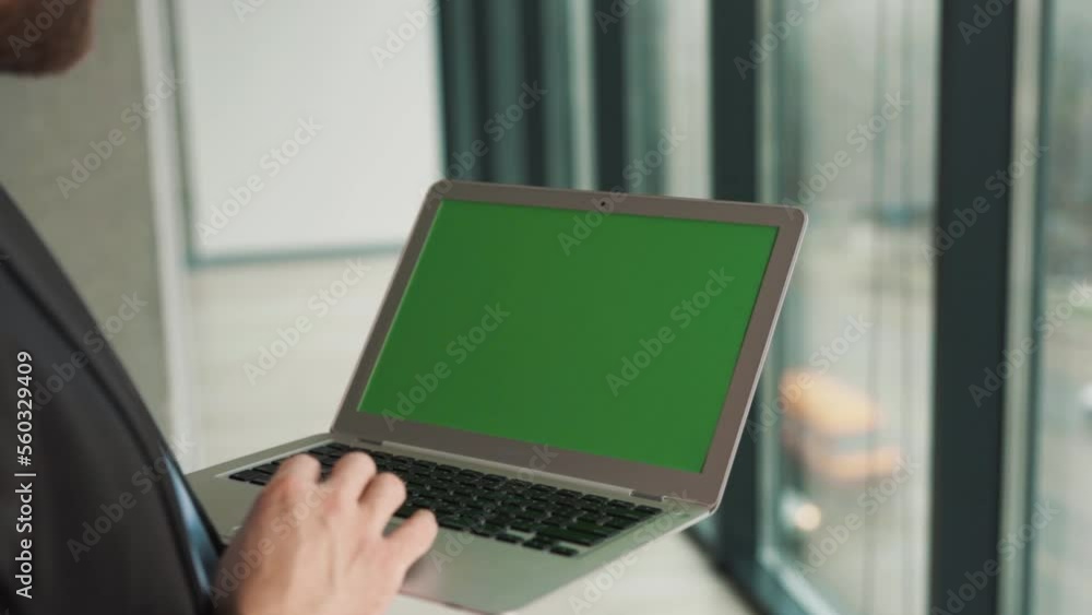 Close-up of a laptop screen with a chromakey in the hands of a man on the background of a panoramic window Close-up of a laptop screen with a chromakey in the hands of a man on the background of a panoramic window