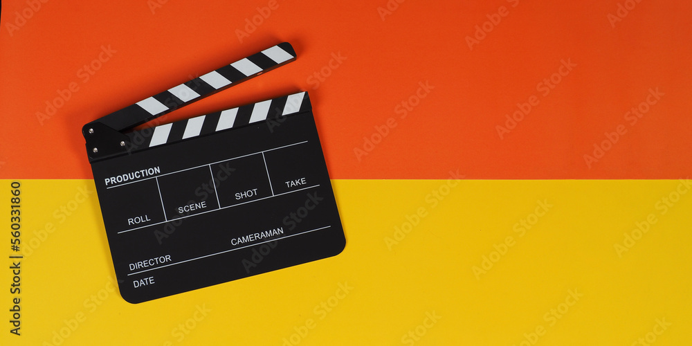 Clapper board or movie slate on yellow and orange background.