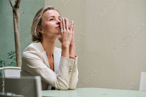 Worried woman thinking about something while sitting at a table outdoors.